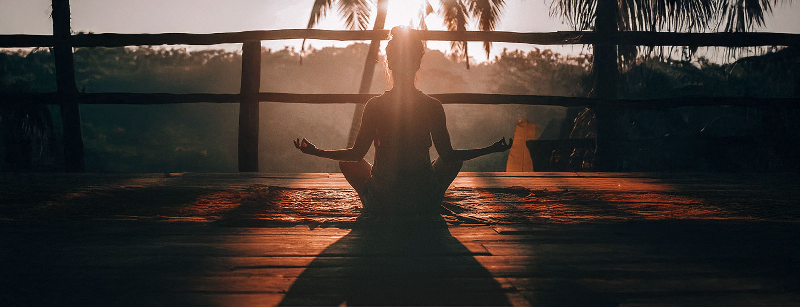 A silhouetted woman meditating at sunset outdoors