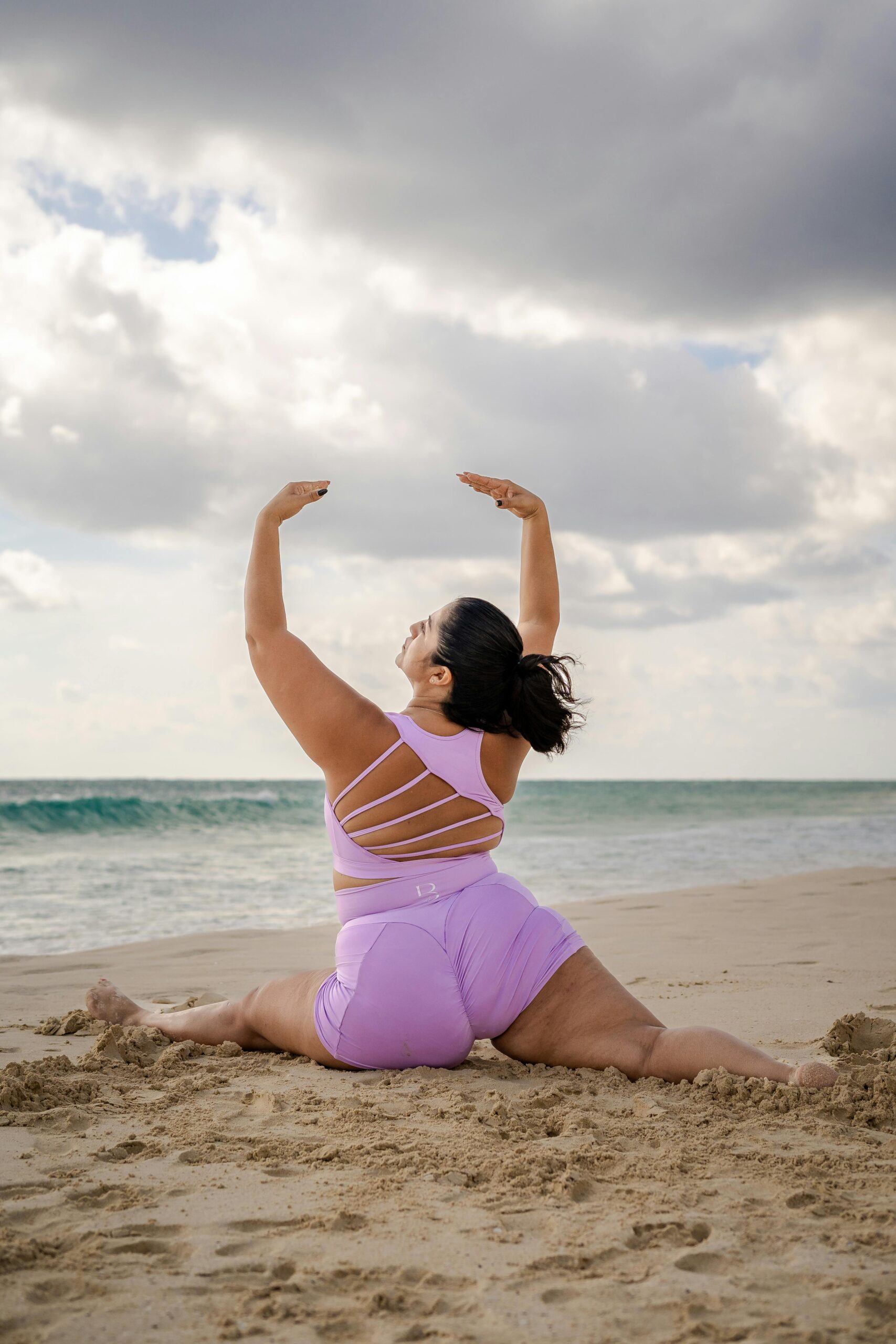 Woman doing a full split stretch on the beach.