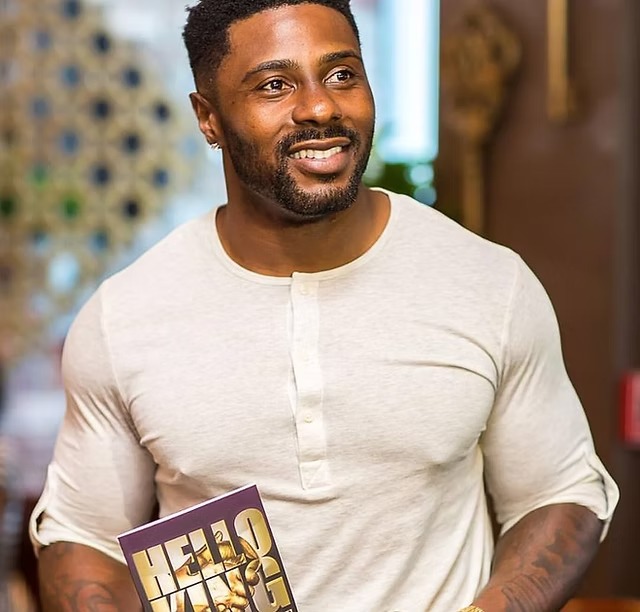 King Jay-Barnett smiling while holding a book.